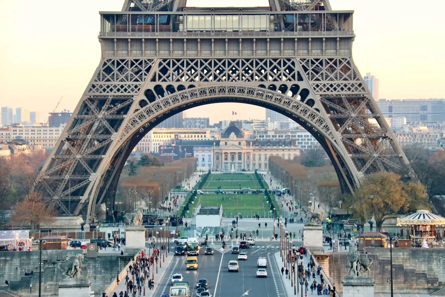 People and cars passing by, near the lower stage of Eiffel Tower